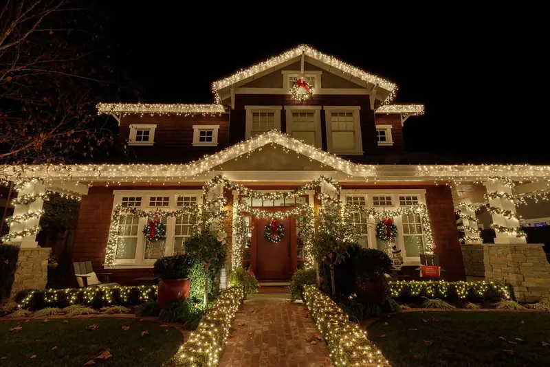 A craftsman-style home with white lights along every roofline and the front path
