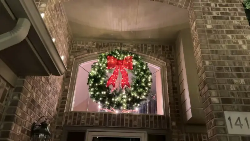 A lit wreath with a red bow above a brick front entrance